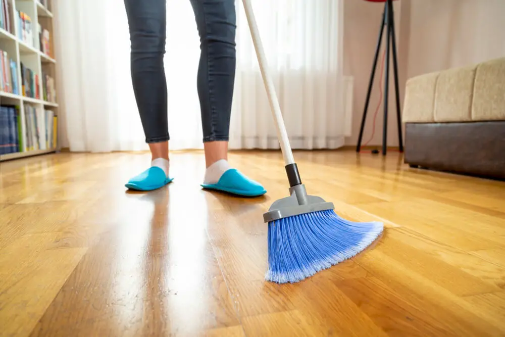 holding a broom and sweeping floor
