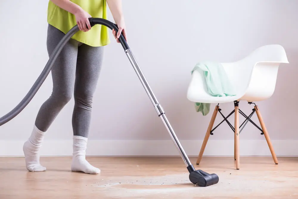 woman vacuuming the dust of the floor